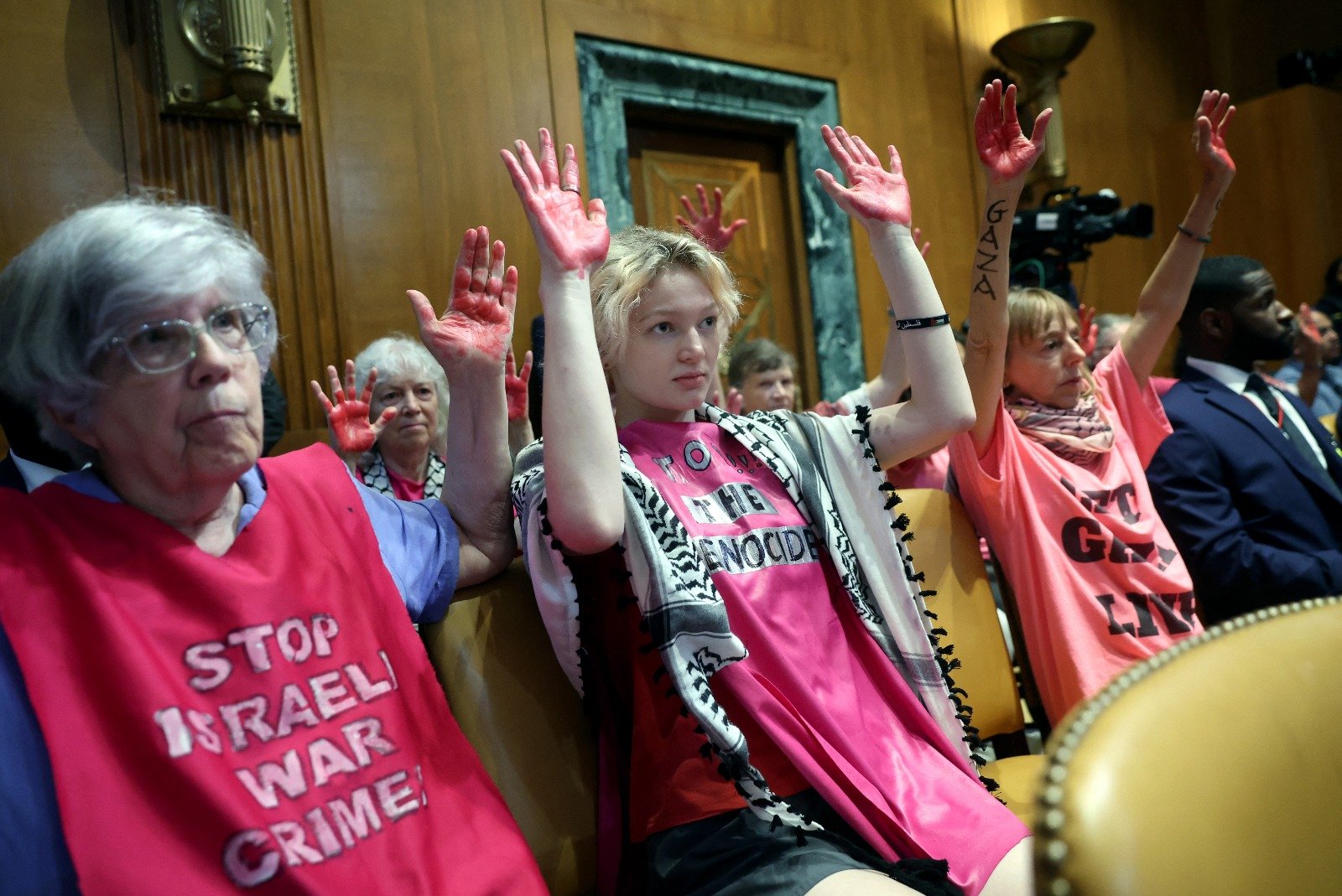 在防长奥斯汀出席国会参议院拨款委员会听证会作证时，一群挺巴勒斯坦示威者高举用染料染红的双掌。（图取自法新社）